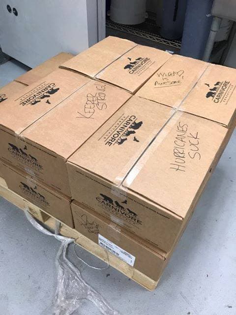 A pallet full of zoo animal food with handwritten blessings from zookeepers on the box