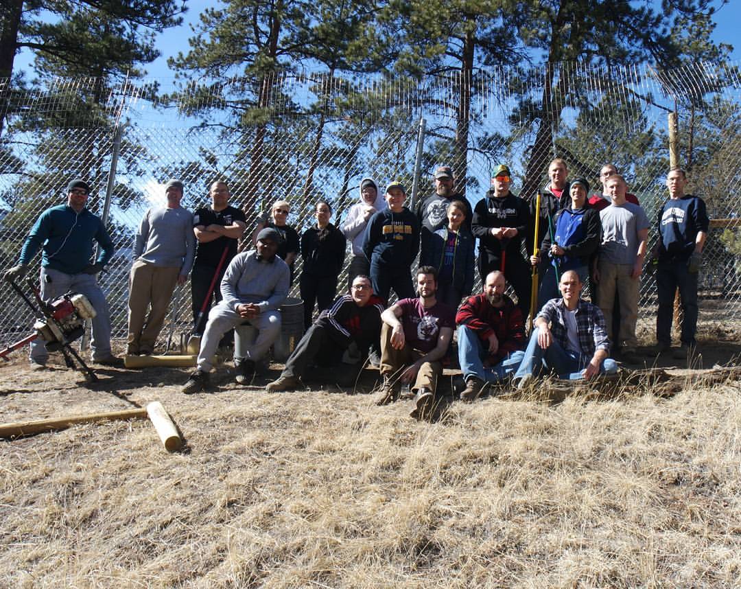 A group photo of volunteers in front of a fence