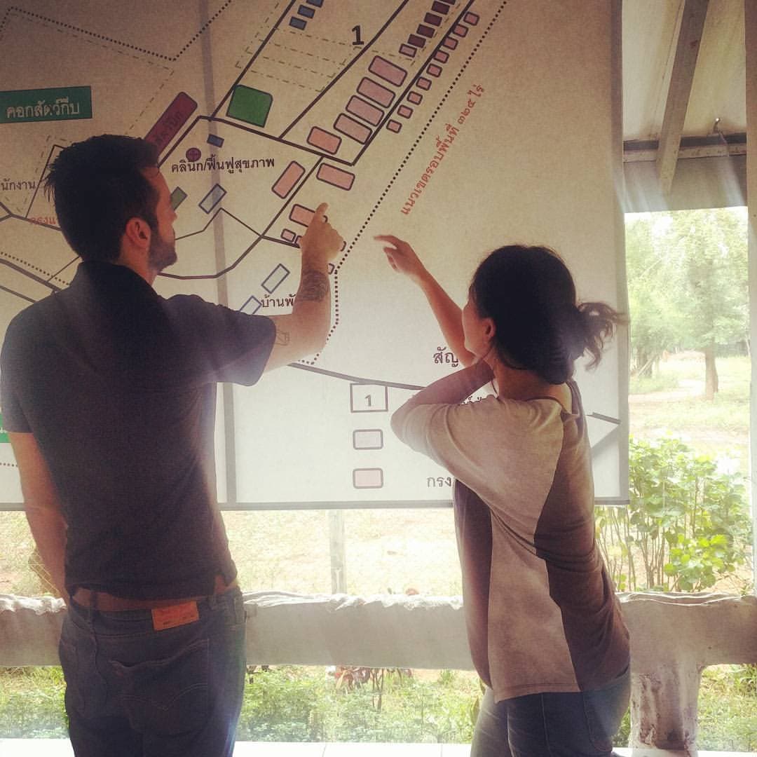 Two volunteers pointing at an empty spot on a map of a wildlife facility with labels written in Thai