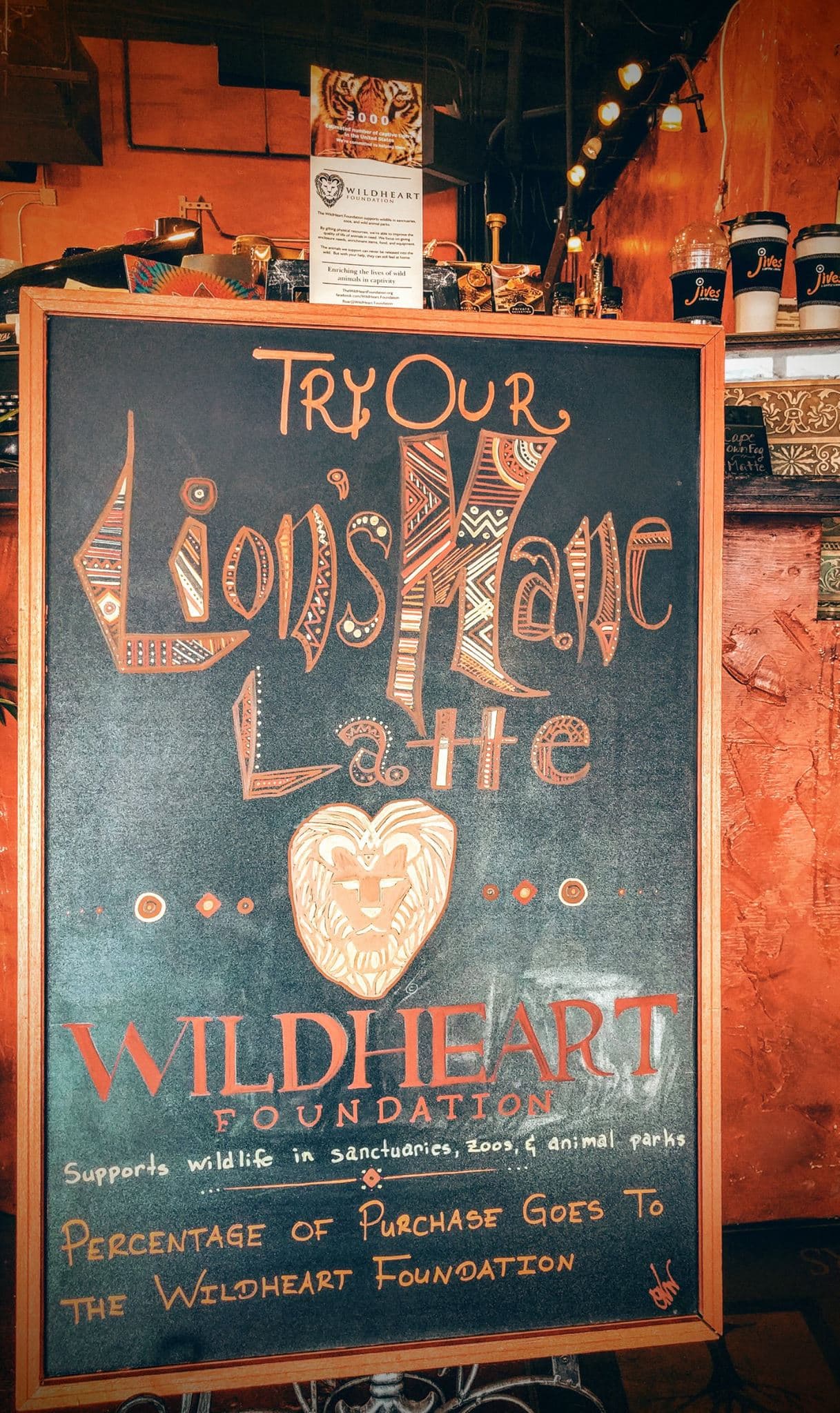 A sign in a coffee shop advertising the Lion's Mane Latte, with proceeds benefitting WildHeart Foundation